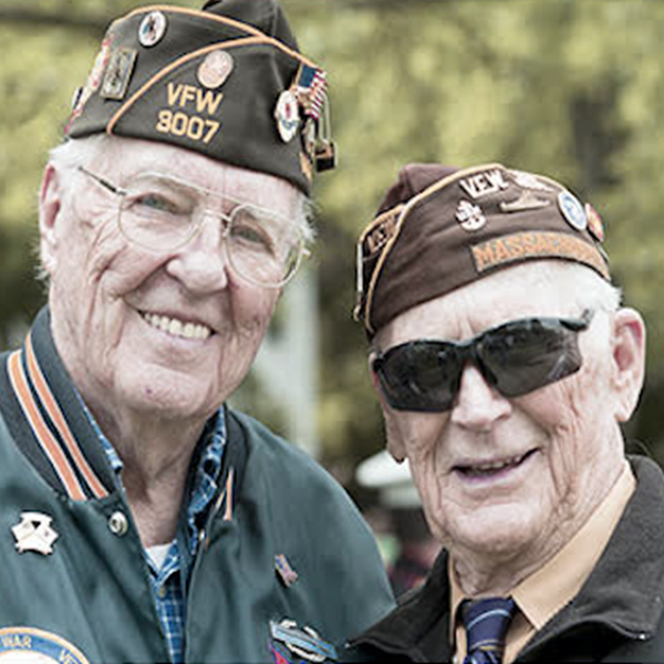 Two senior veterans in military uniforms smiling